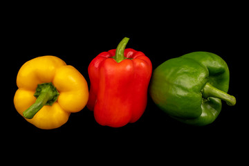Кed, yellow, green paprika (pepper) isolated on a black background