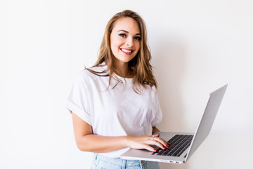 Naklejka premium Young happy smiling woman in casual clothes holding laptop isolated on white background
