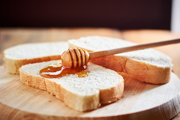 Pouring fresh honey on bread slices