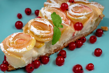 A slice of Apple pie with roses and currants close-up