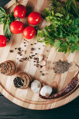 Spices: chili, black pepper, garlic, cumin, coriander, sweet pepper lie on a brown round wooden board on a black table. Place under the text.