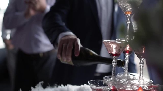 People pouring wine to pyramid tower of glasses with champagne
