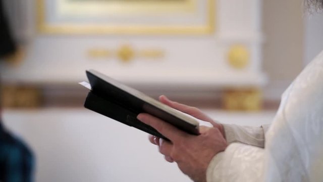 Priest praying with Bible book in church at ceremony
