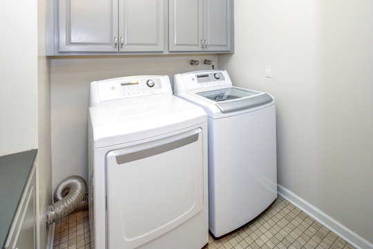 Clean and organized laundry space with gray cabinets.