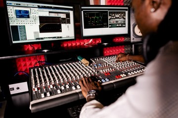 African musician with dreadlocks adjusts the sound on the mixing console in the recording studio