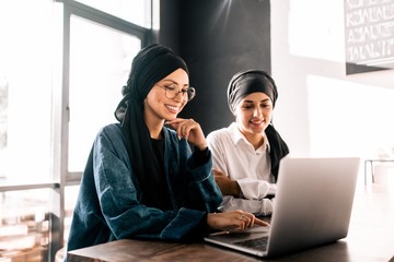 Muslim women hijab working at laptop sitting in office