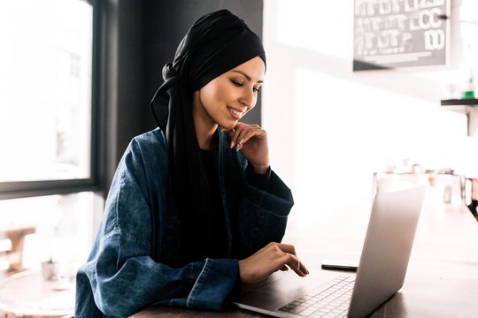 Muslim girl hijab typing on laptop sitting in office
