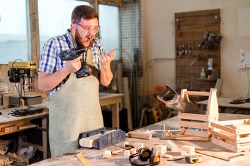 Bearded carpenter in goggles hurt your hand drill is not observing safety