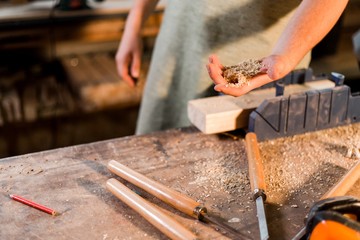 Carpenter holding wood sawdust standing in the carpenter's shop close-up