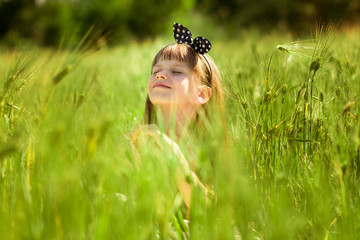 Portrait of beautiful little girl in middle of green summer field