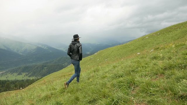 woman in a black hat and a leather jacket walking