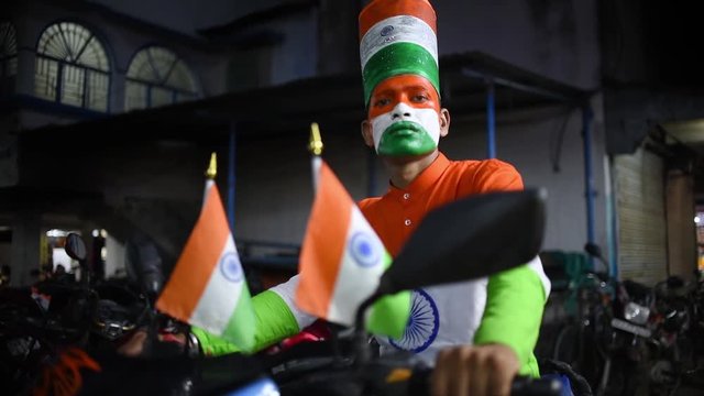 An Indian man with Indian flag tricolor face paint and tricolor shirt and hat sitting on a bike on Indian Independence day and republic day, Slow motion