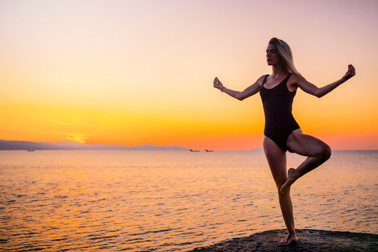 Silhouette of a girl doing yoga on the pier by the sea, standing asana Vrikshasana at sunrise. Healthy lifestyle. © indigo_nifght