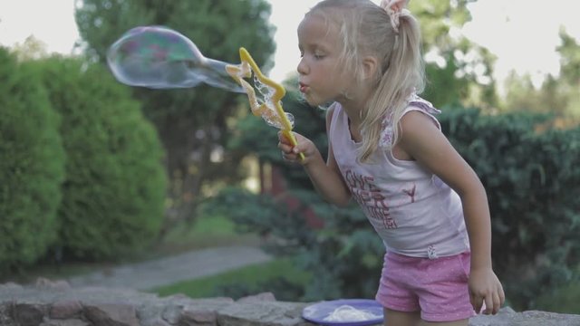little girl blowing soap bubbles in summer park. fullhd slow motion video shooting by handheld gimbal