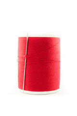 Spool of red thread and needle on white background