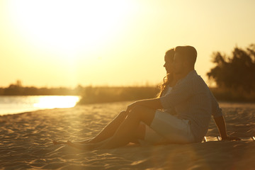 Fototapeta na wymiar Happy young couple resting together on beach at sunset