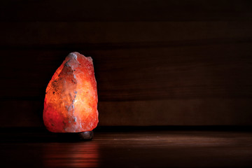 Himalayan salt lamp glowing on dark background with space for text