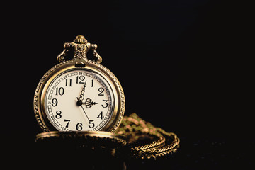 Antique pocket watch on black background.