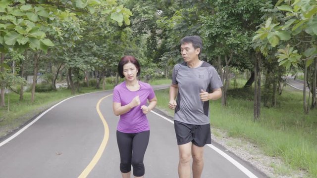 Asian middle aged couple jogging and running in park