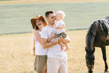 A young family have a fun in the field. Parents and child with a horse