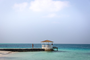 Maldives, Feb 3rd 2018 - Beach umbrellas at the shallow blue water with some divers enjoying the tropical weather of Maldives