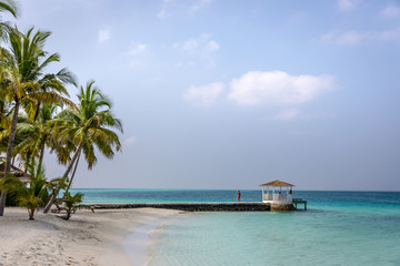 Maldives, Feb 3rd 2018 - Beach umbrellas at the shallow blue water with some divers enjoying the tropical weather of Maldives