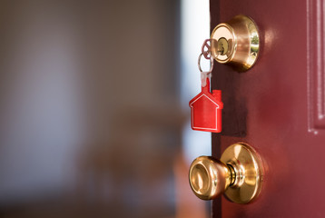 House key with house shape keychain in the door