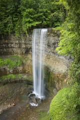 Tall ribbon waterfall flowing softly over sedimentary rock layers