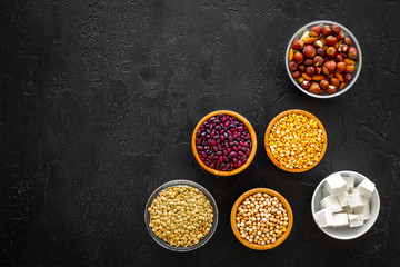 Products rich protein. Legumes, nuts, low-fat cheese. Raw beans, chickpeas, lentil, almond, hazelnut on black background top view copy space