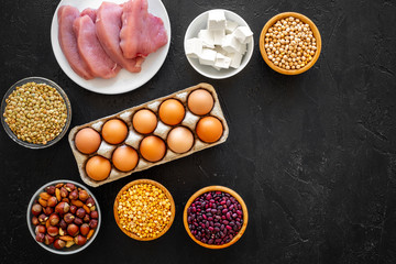 Food for sportsmen. Legumes, nuts, low-fat cheese, meet, eggs on black background top view copy space