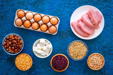 Food for sportsmen. Legumes, nuts, low-fat cheese, meet, eggs on blue table top view