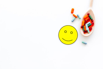 Reception of medicines concept. Recovery. Pills in spoon near smile face emoji on white background top view copy space