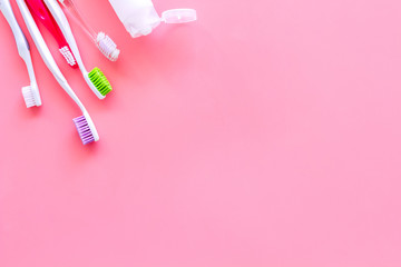 Teeth care, dental care. Toothbrushes and tooth paste on pink background top view copy space