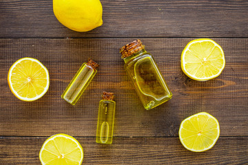 Natural cosmetics. Lemon essential oil near halfs os lemons on dark wooden background top view...