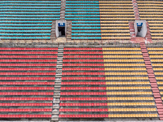 Fototapeta premium empty colorful plastic chairs in row at the football stadium. aerial view 