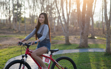 Fototapeta premium Beautiful asian girl with mountain bike in the park ,sunshine flare