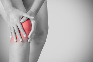 Young woman touching an inflamed knee with pain isolated with clipping path, Health care and...