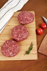 Raw cutlet of minced meat on a wooden cutting board.