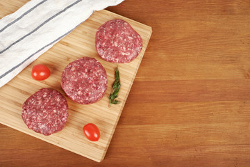 Raw cutlet of minced meat on a wooden cutting board.