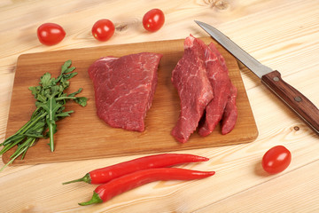 Sliced raw beef on cutting board and vegetables