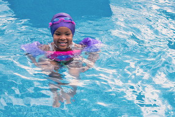 A young African girl is enjoying swimming at summer time