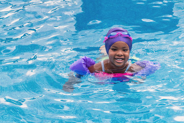 A young African girl is enjoying swimming at summer time