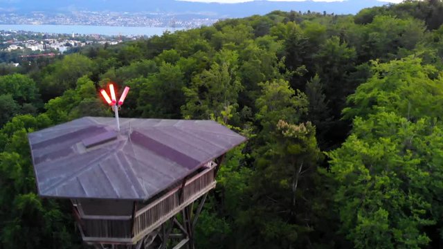 4K Aerial drone shot of a tower in the green forest of the city of Z&uuml;rich. The drone is flying around the tower. There is a view of the beautiful forest and nature of Switzerland.