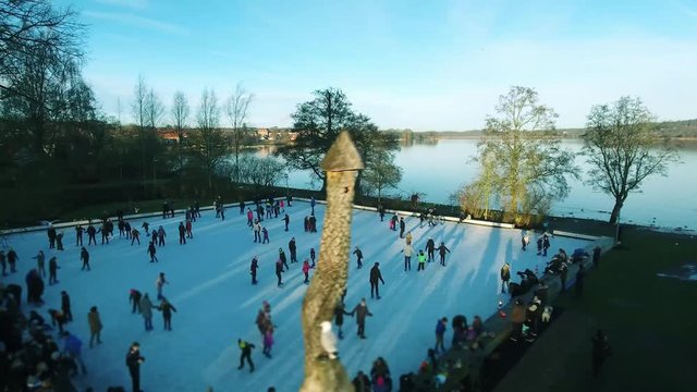 Drone footage of people ice skating late afternoon, people having fun and enjoying them selfs.