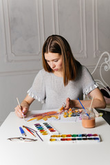 Fototapeta premium Pretty smiling young woman drawing a picture