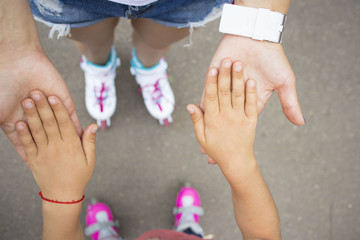little girl on roller skates holding the adult hand of the parent