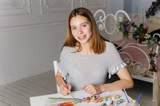 Pretty smiling young woman drawing a picture