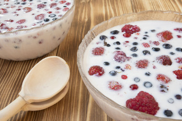 berries in milk on wooden background, healthy food concept