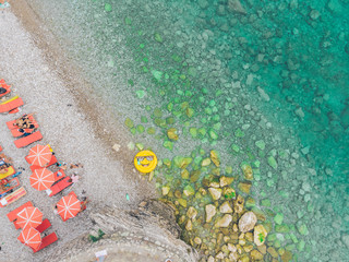 aerial view of seaside with sun loungers and sun umbrellas, yellow inflatable ring with smile