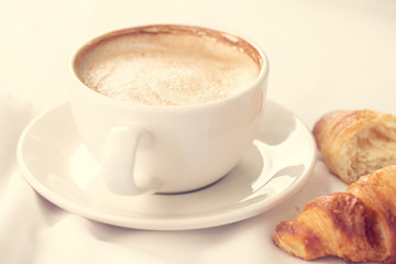 Coffee and croissant for breakfast with shallow depth of field.